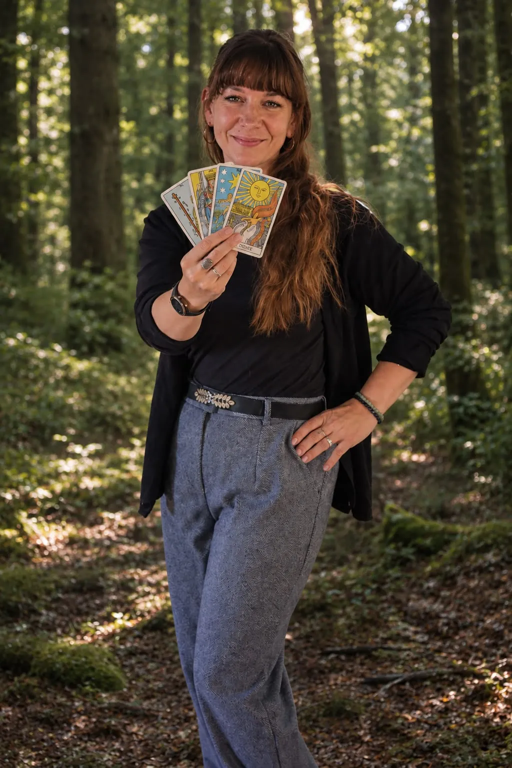 Melanie Lamm hält Tarotkarten in einem Wald